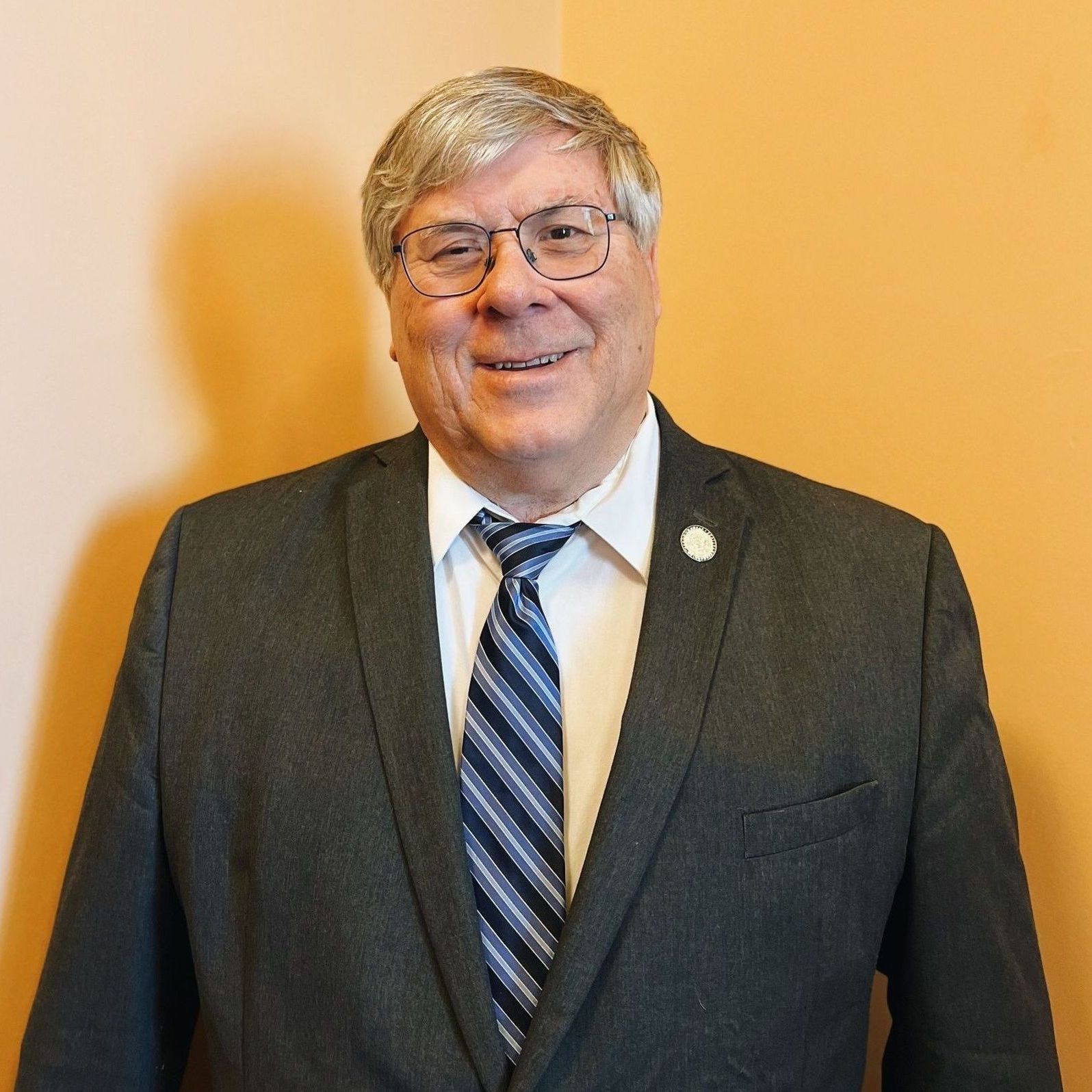 A man in a suit and tie is smiling for the camera