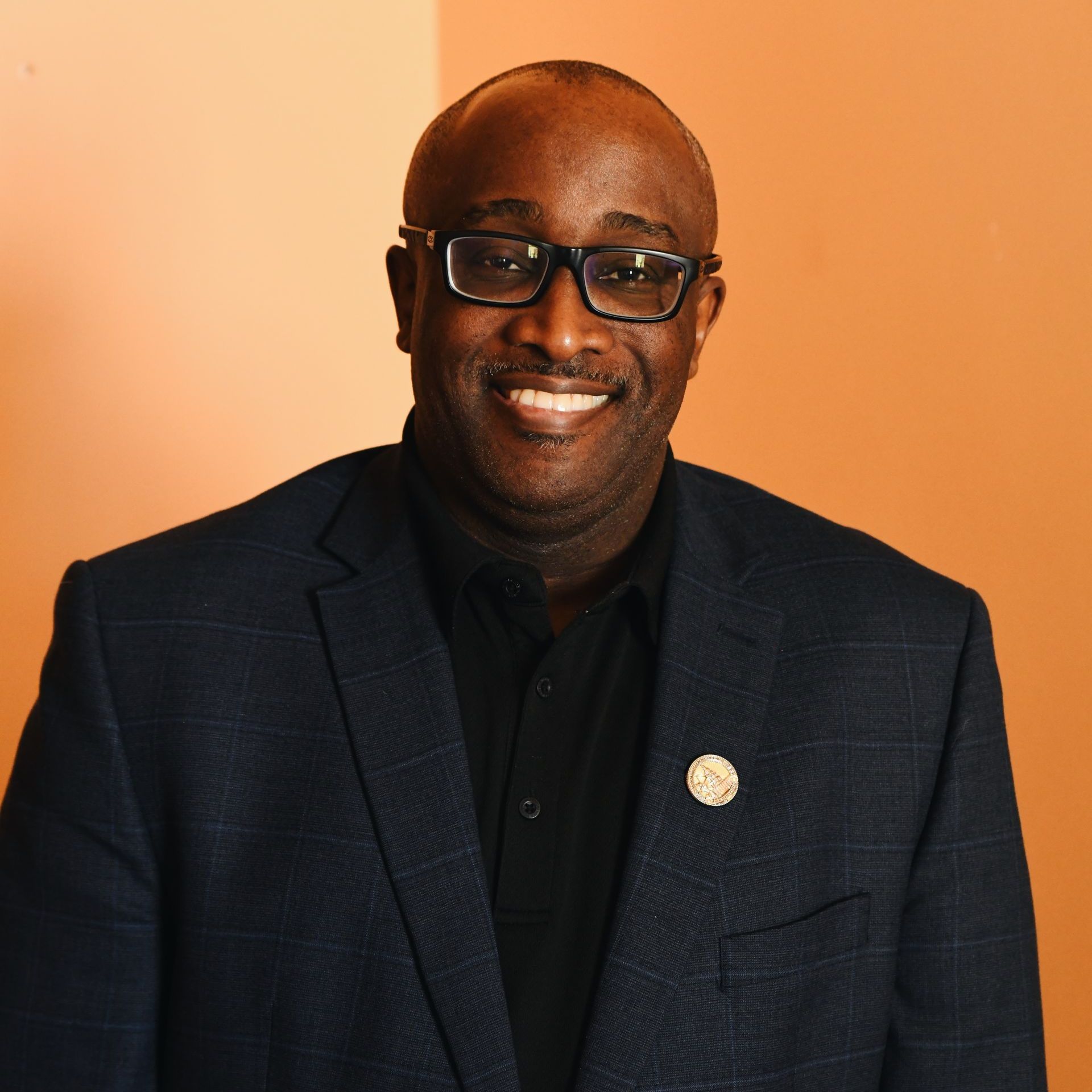 A man in a suit and glasses is smiling for the camera.