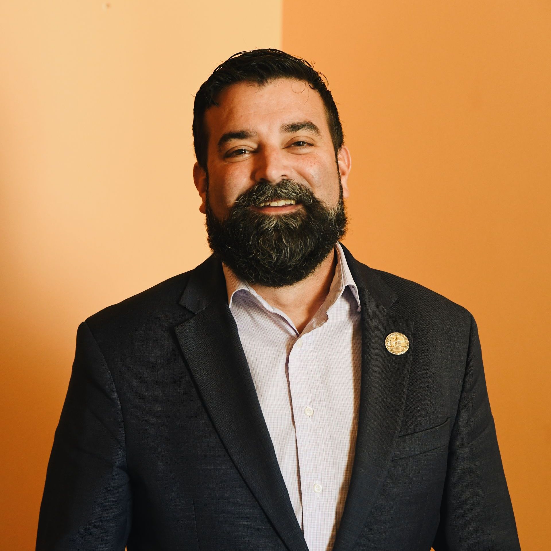 A man with a beard is wearing a suit and smiling
