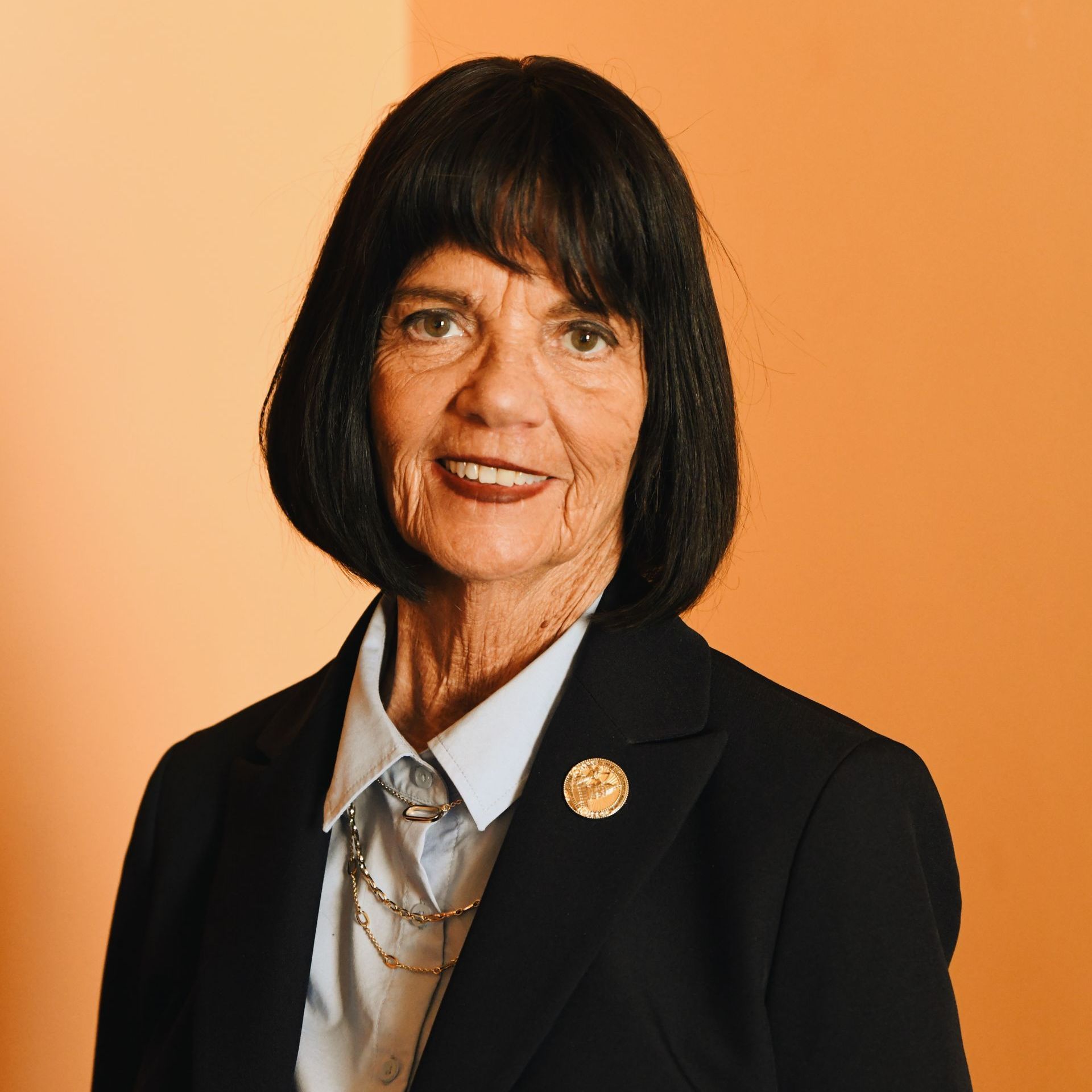 A woman wearing a black jacket and a white shirt is smiling for the camera