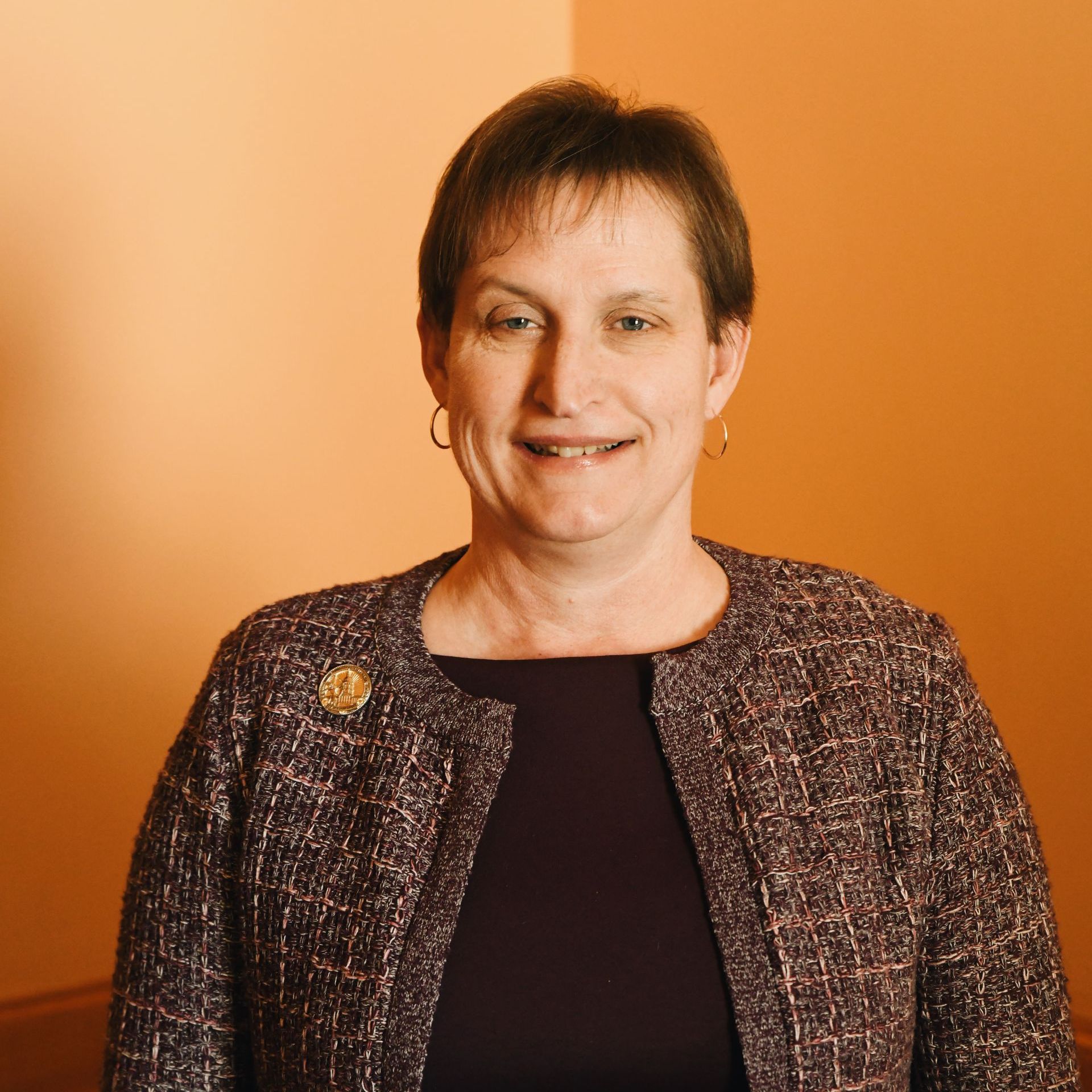 A woman in a purple jacket is smiling for the camera