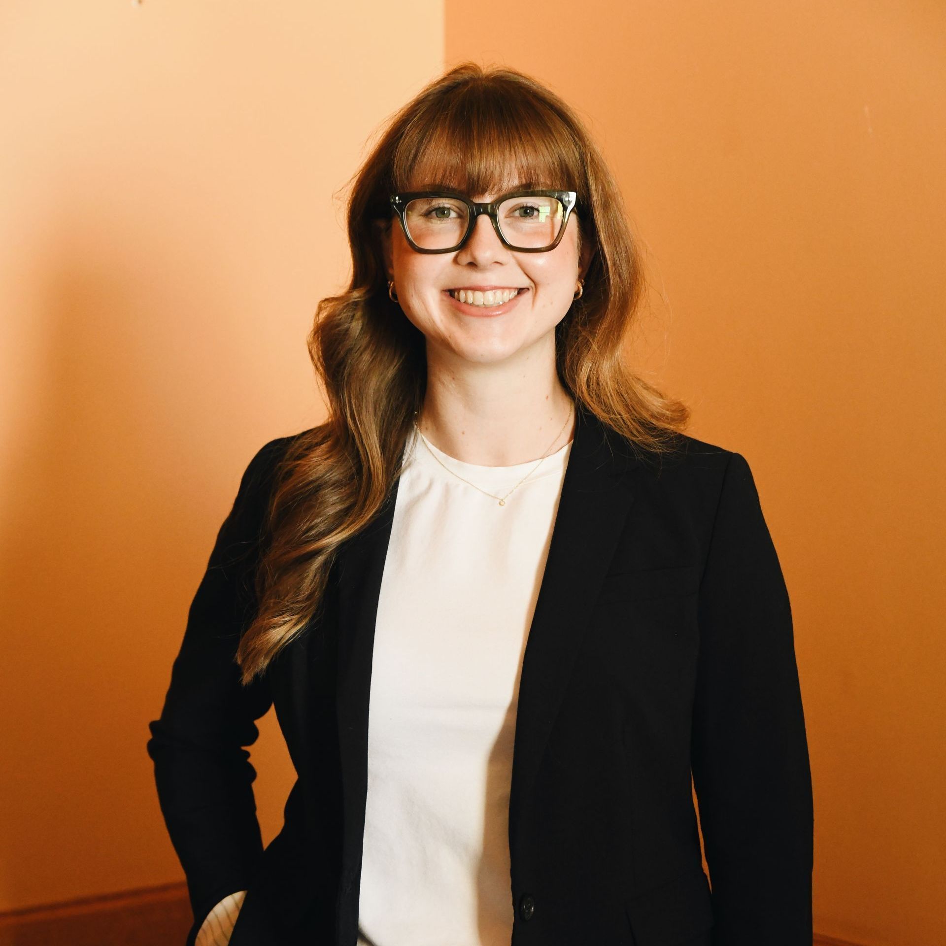 A woman wearing glasses and a black jacket is smiling for the camera.