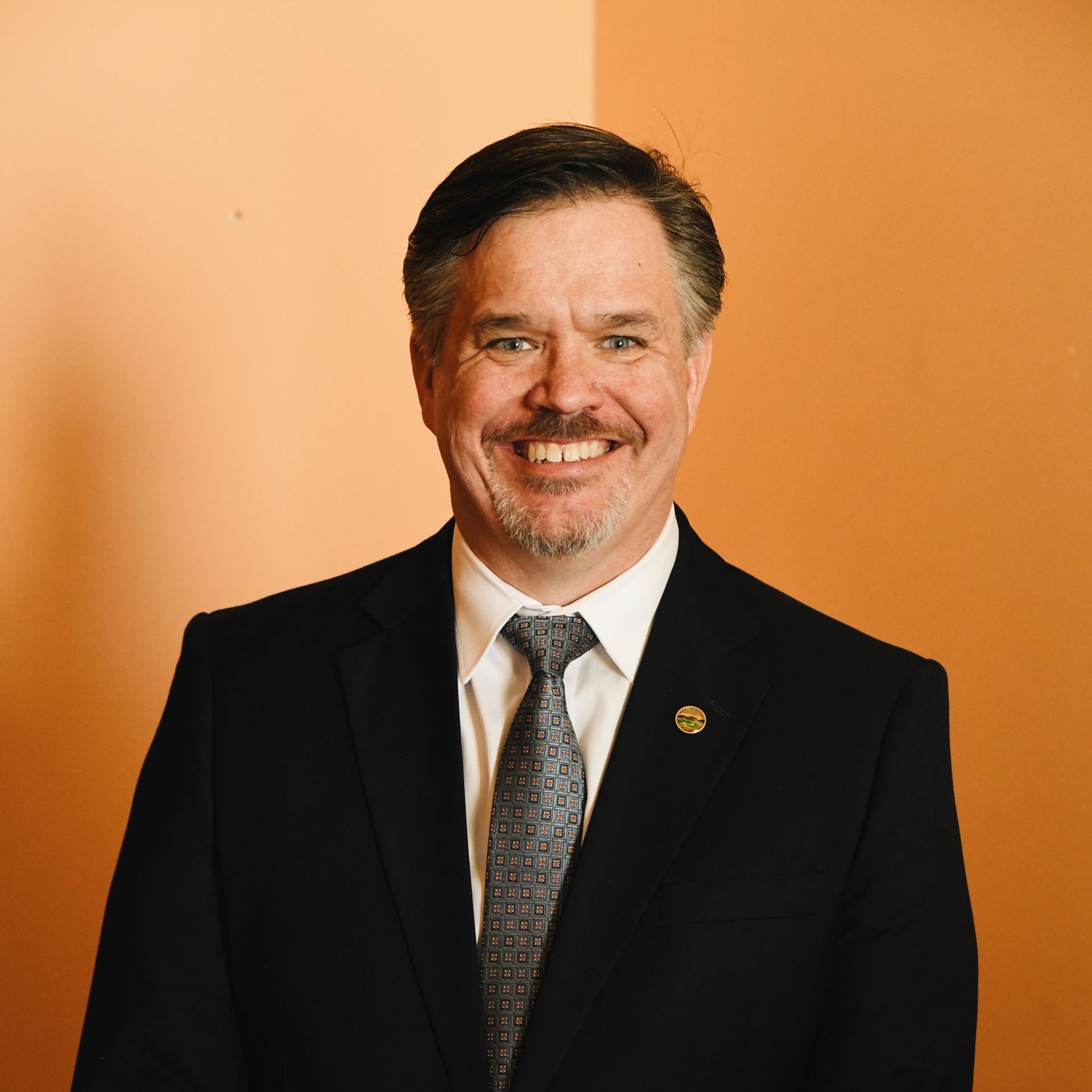 A man in a suit and tie is smiling for the camera.
