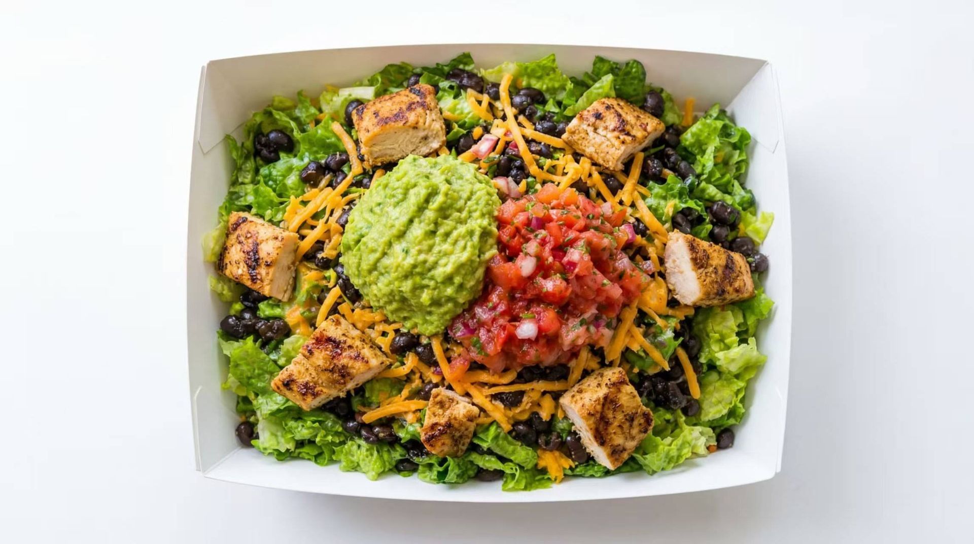 Box of salad with greens, grilled chicken, shredded carrots, guacamole, and salsa