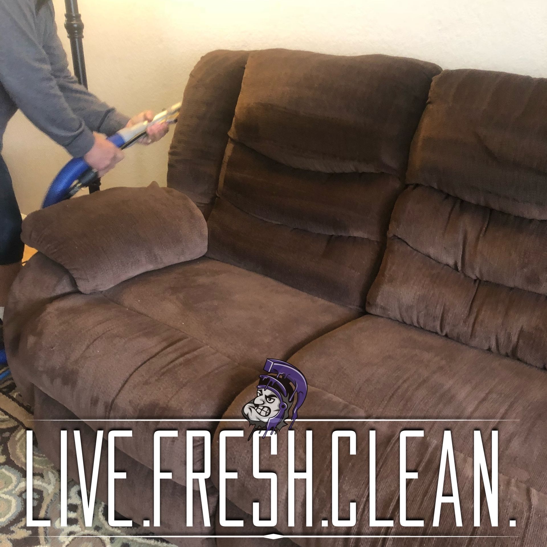 Person cleaning a brown couch with a vacuum. 
