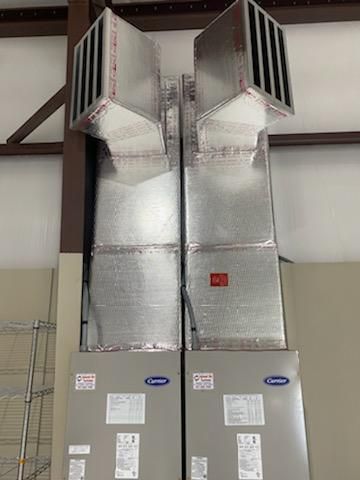 Two air conditioners are stacked on top of each other in a building.