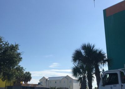 A moving truck is parked in front of a building next to palm trees.