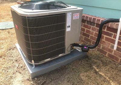 A large air conditioner is sitting on top of a concrete platform next to a brick wall.
