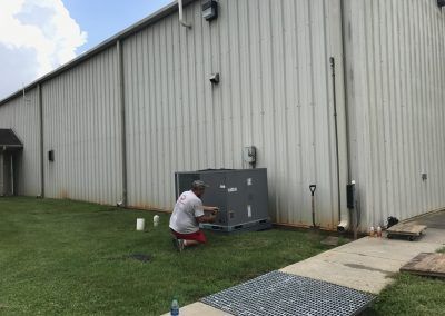 A man is working on an air conditioner outside of a building.