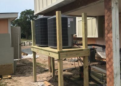 Two air conditioners are sitting on top of a wooden platform.