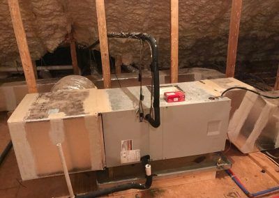 An air conditioner is sitting in the attic of a house.