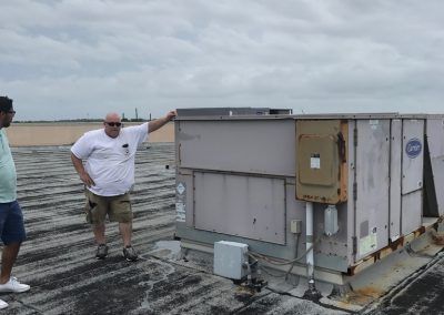 Two men are standing on top of a roof next to a large box.