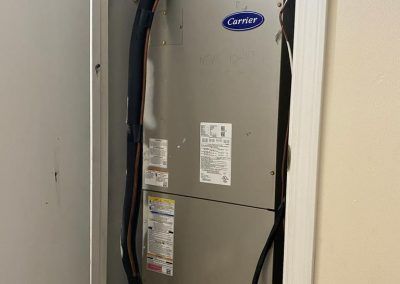A carrier air conditioner is sitting in a closet next to a wall.