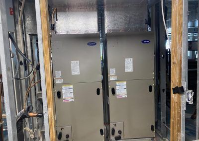 Two air conditioners are stacked on top of each other in a room.