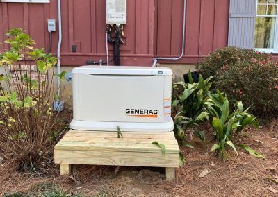 A generator is sitting on a wooden platform in front of a house.