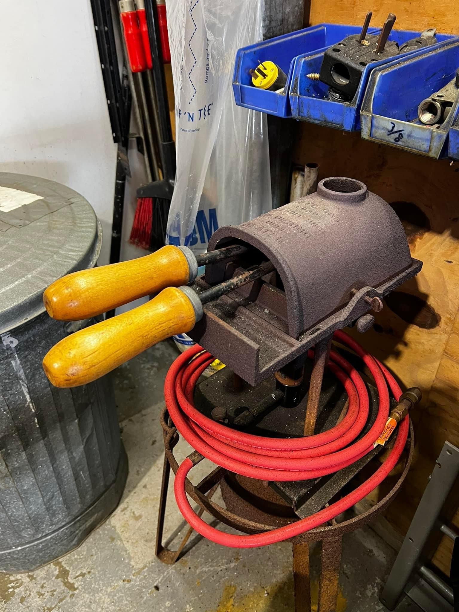 A pair of screwdrivers sitting on top of a metal object next to a red hose.