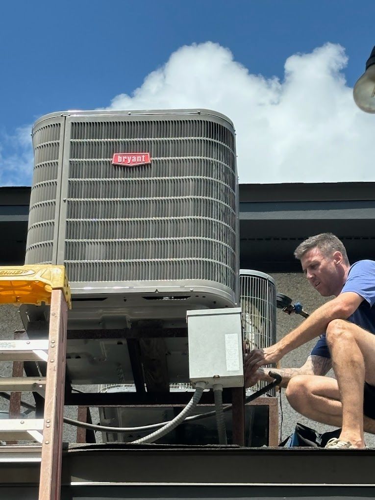 A man is working on an air conditioner on the roof of a building.