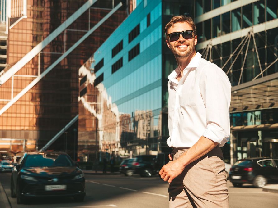 Man in a downtown city with tall glass skyscrapers under a clear blue sky