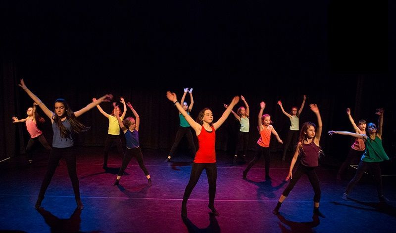 Young dancers exhibiting contemporary dance technique, musicality, and agility in a public performance