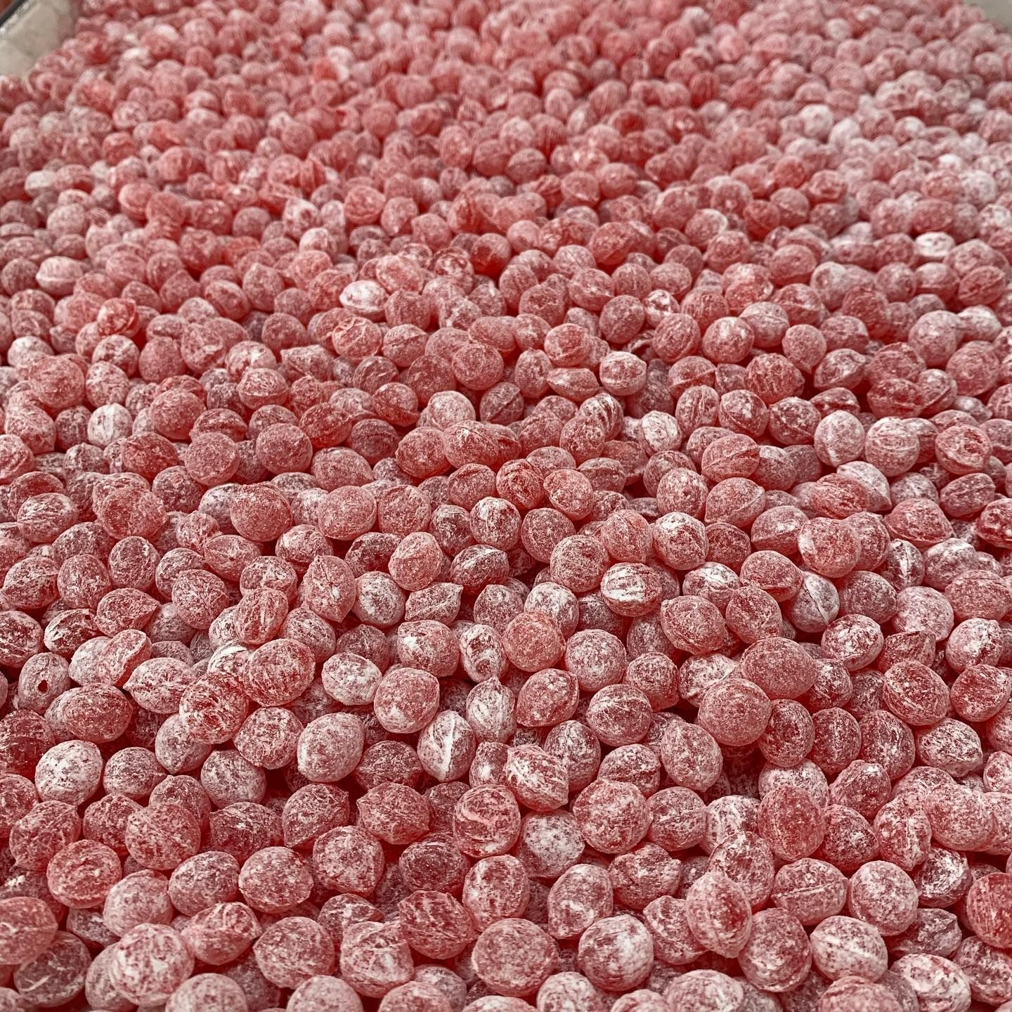 A pile of red candy balls sitting on top of each other on a table.