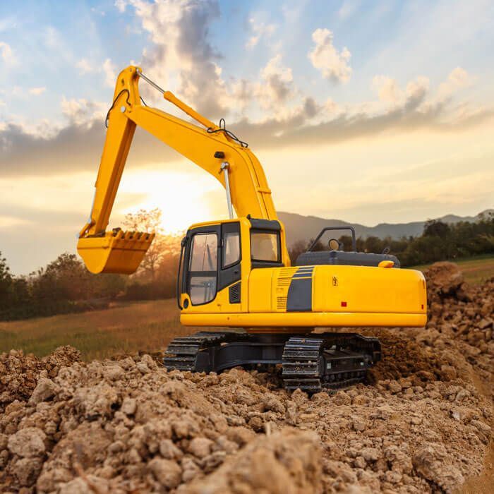 yellow excavator on a pile of dirt