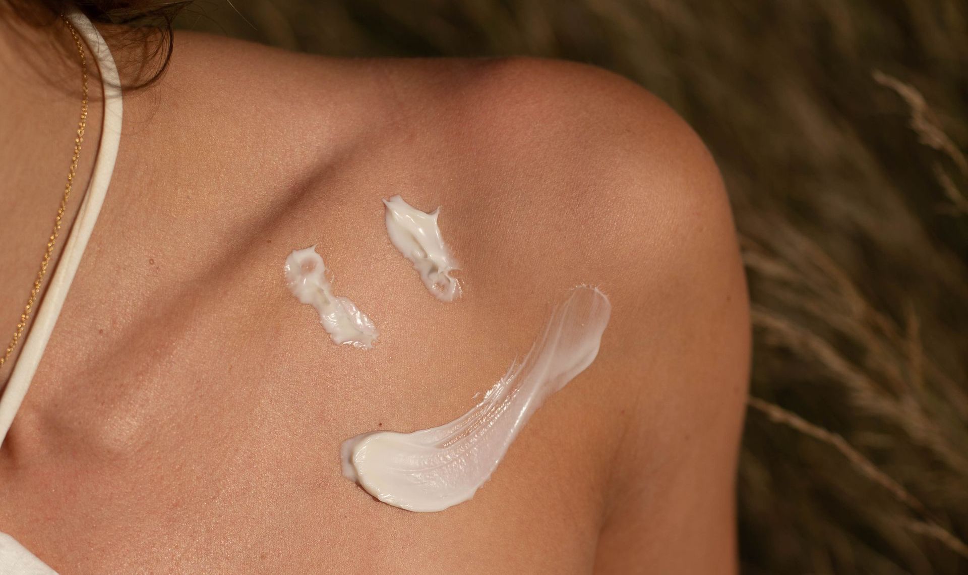 Close-up van zonnebrandcrème aangebracht op een blote schouder.