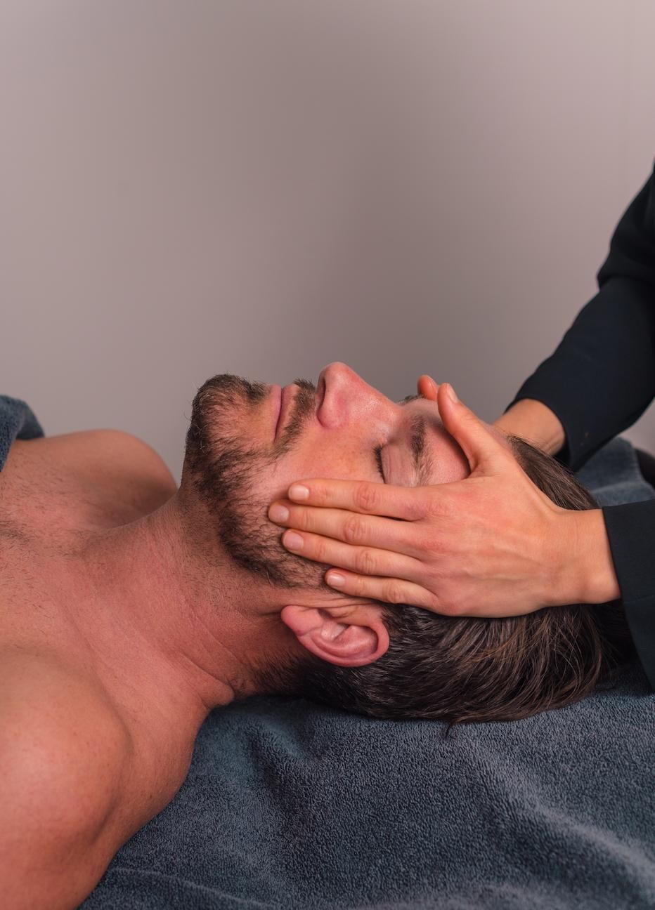 Een persoon die een gezichtsmassage krijgt terwijl hij op een donkere handdoek ligt.
