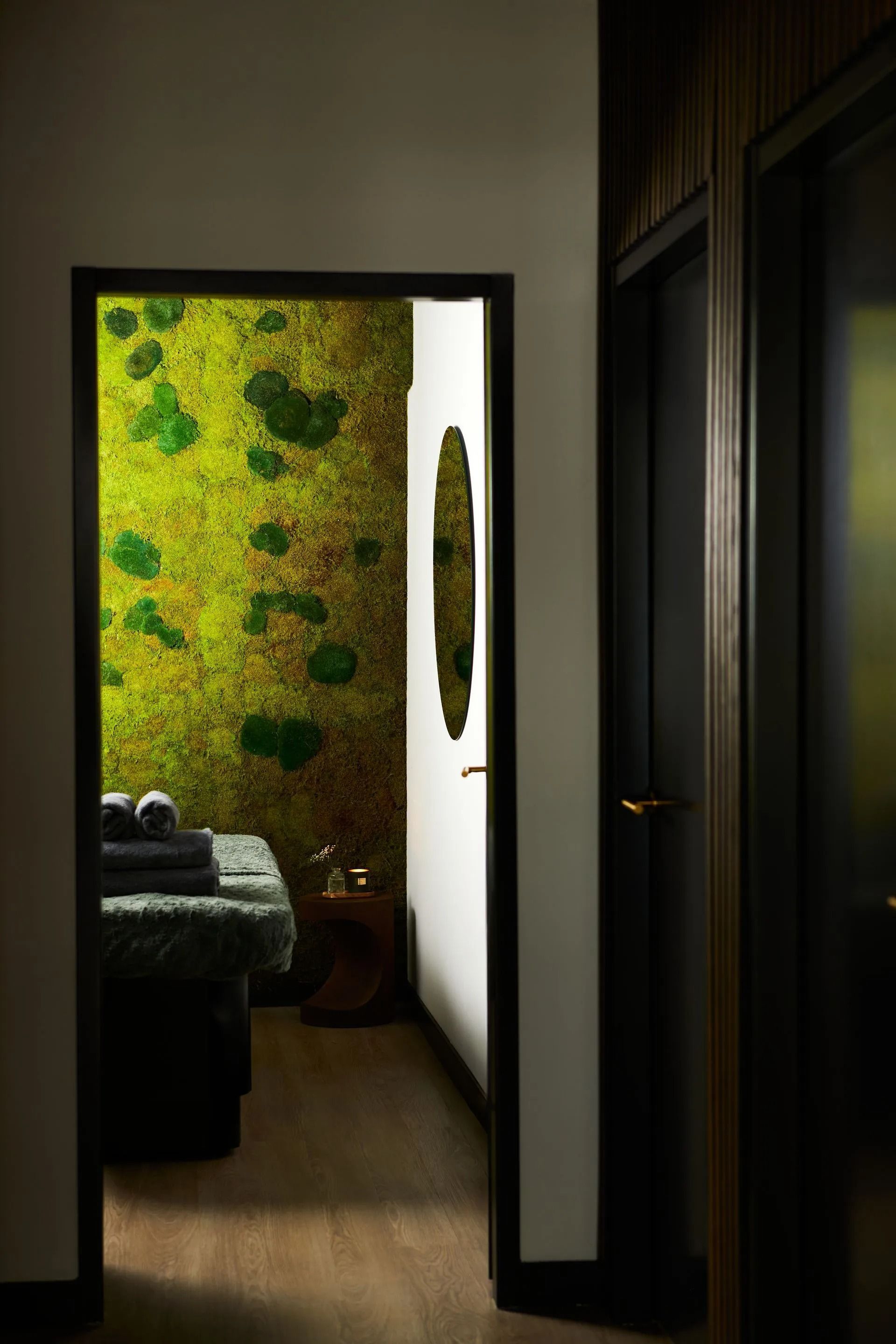 Een schemerig uitzicht vanuit de gang op een slaapkamer met een groene bloemenaccentmuur en een open deur.