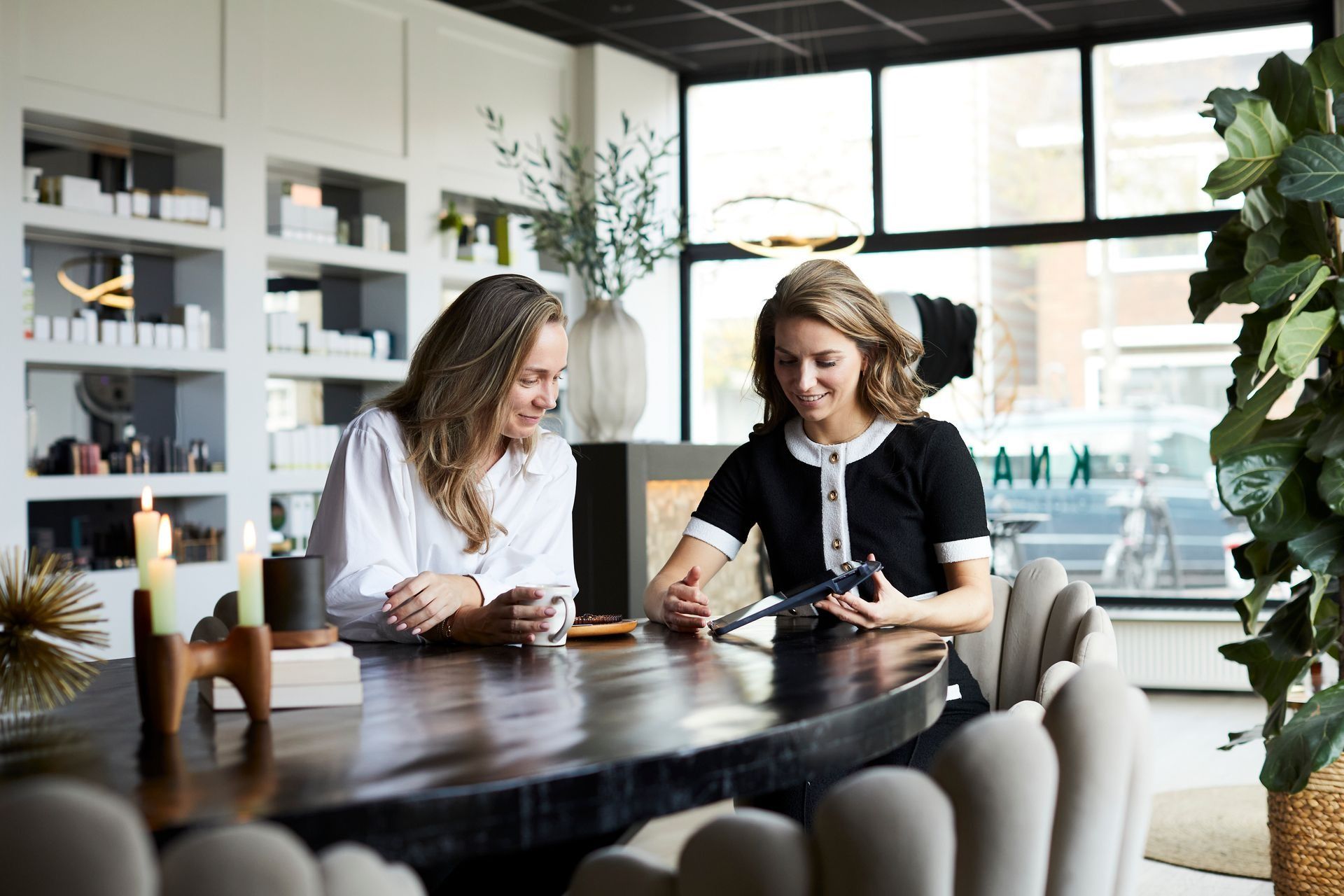 Twee mensen schrijven aan een houten tafel in een licht, modern café.