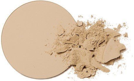 Beige compact poederschijfje naast een hoopje gebroken poeder op een witte achtergrond