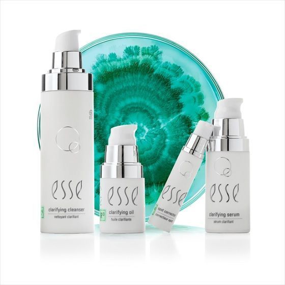 Essé huidverzorgingsset met witte flesjes en potjes voor een turquoise ronde achtergrond.