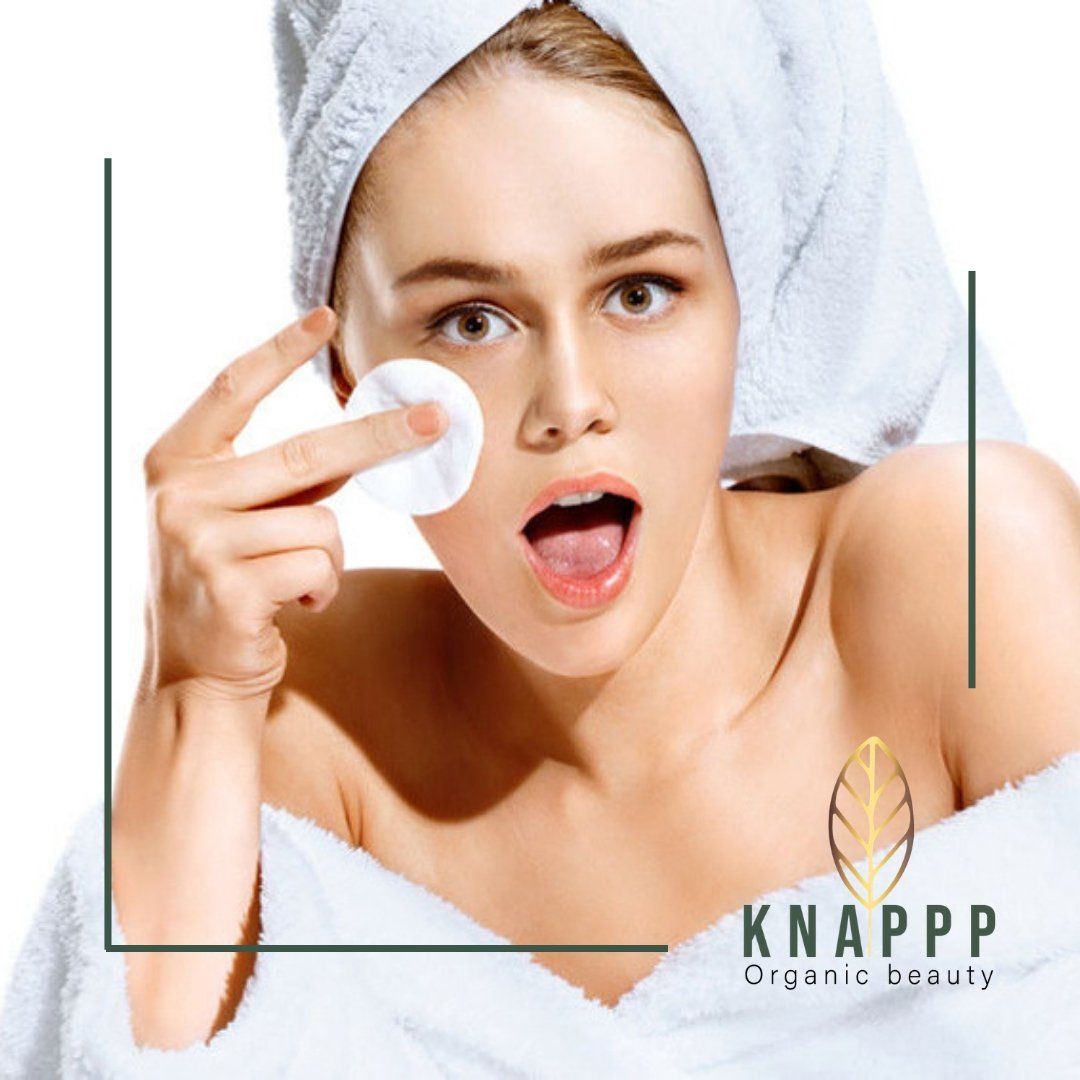 Vrouw met handdoekhoofdband die een wattenschijfje op haar gezicht aanbrengt, met Knapp Organic Beauty-logo.