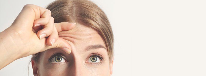 Close-up van een persoon die over zijn voorhoofd wrijft, boven zijn ogen, wat wijst op stress of vermoeidheid.
