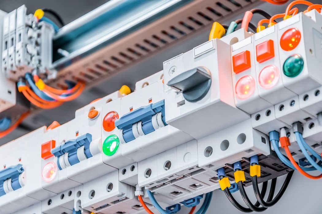 Pannello di controllo industriale con interruttori, spie luminose e cablaggio in un ambiente di fabbrica.