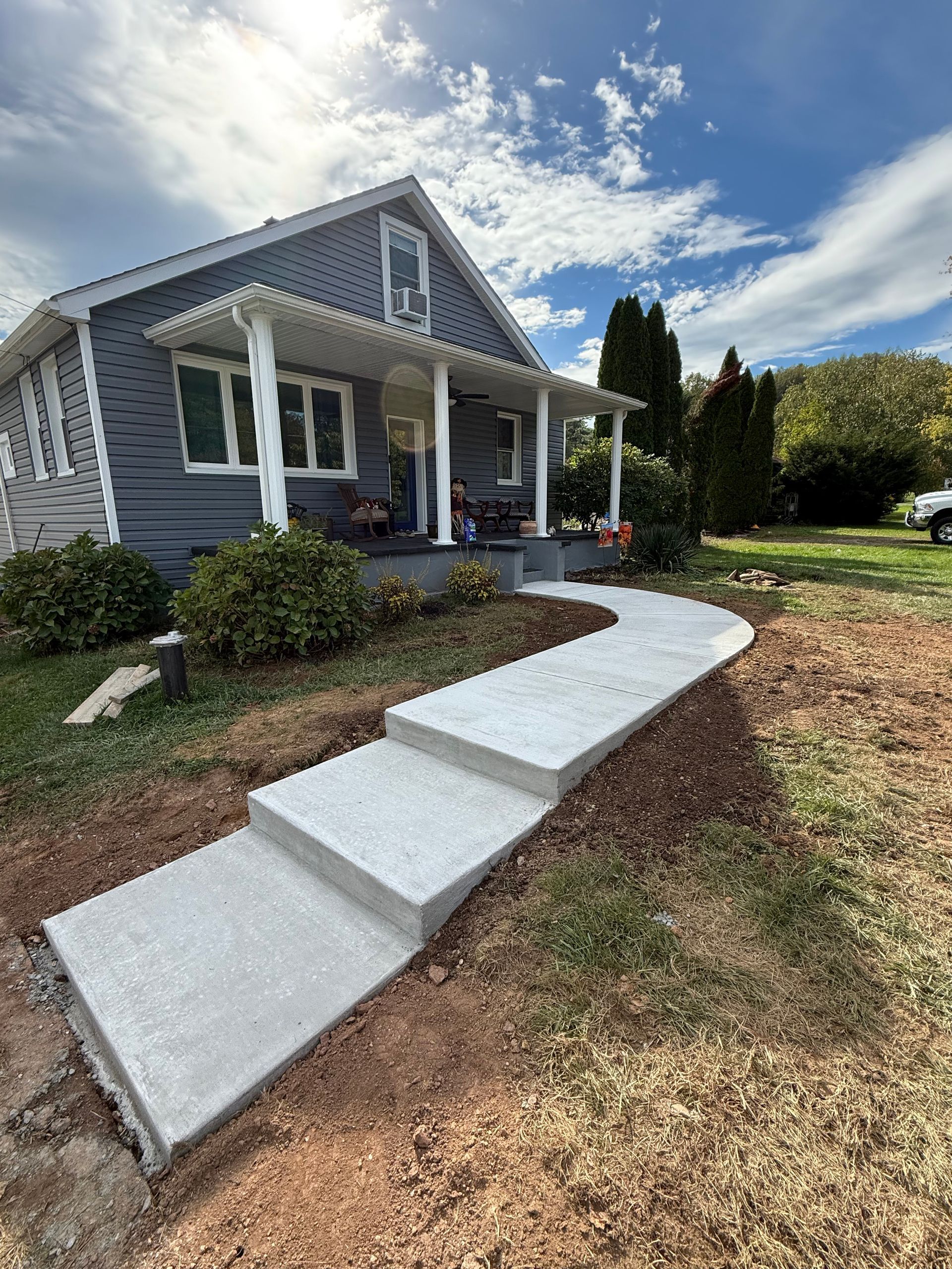A concrete walkway leading to a house with a lush green lawn.
