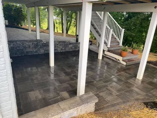 Covered patio with dark tile floor, white columns, and steps leading to a garden area