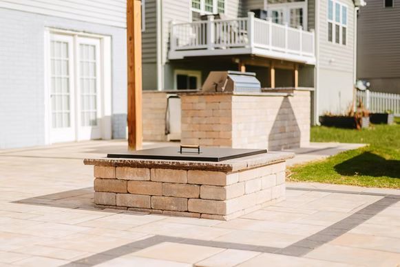 Stone outdoor fireplace on a patio beside a house and deck