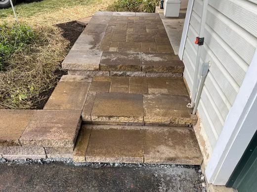 Uneven concrete walkway with raised, cracked slabs beside a house exterior.