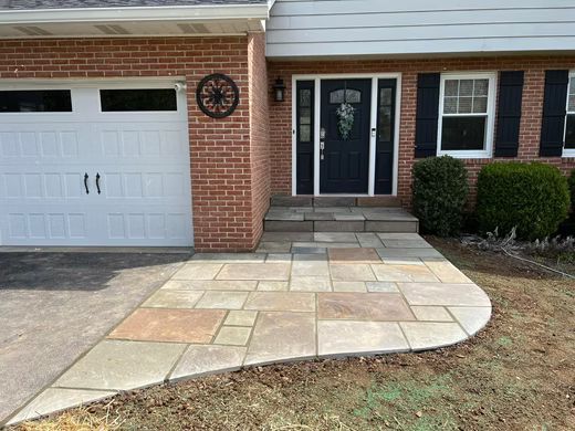 Front walkway of a suburban house with a curved stone patio leading to the front door and garage.