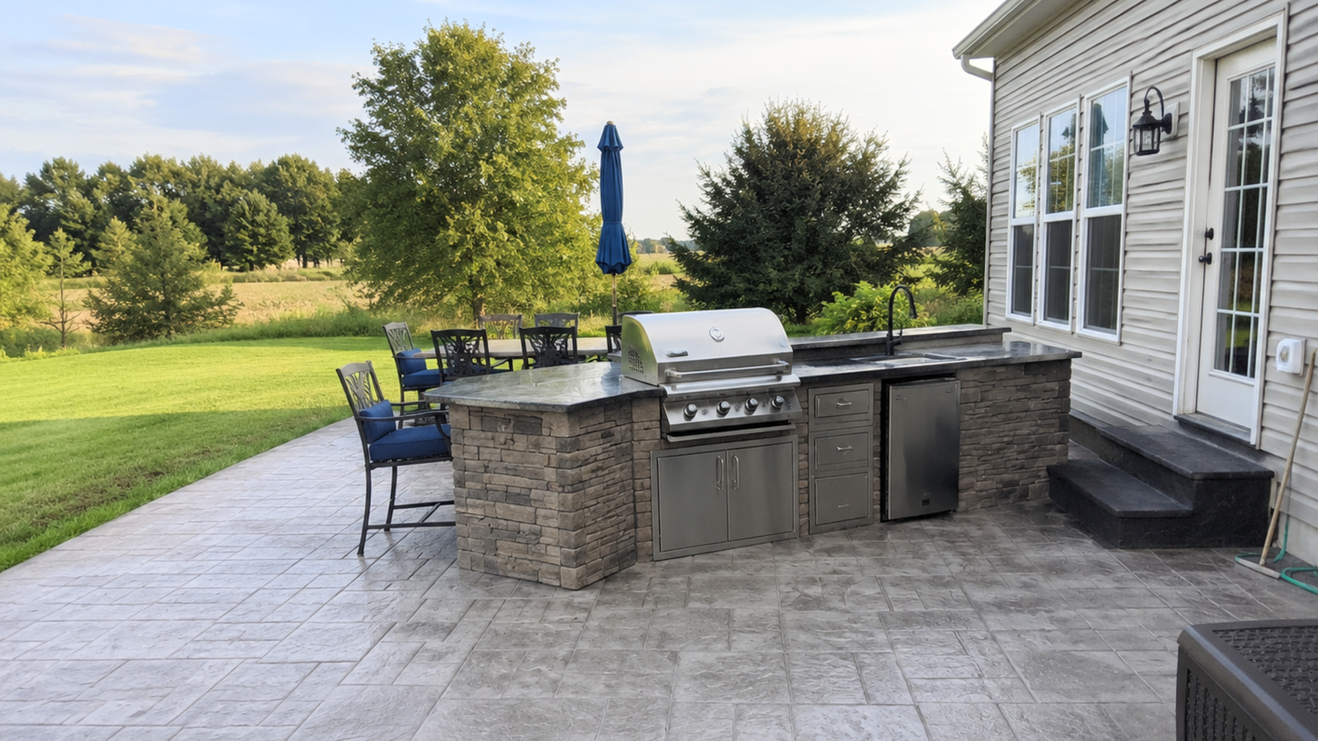 Stamped concrete patio with built-in stone outdoor kitchen
and stainless steel grill in a Frederick County, MD backyard