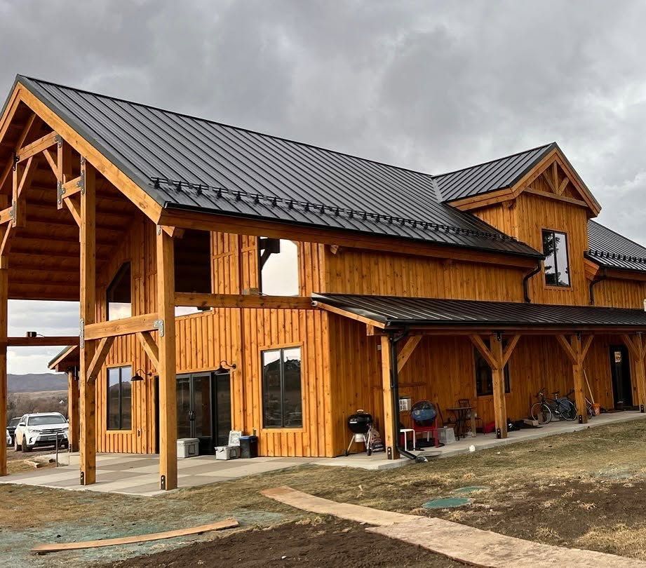 Rustic wooden house with a dark metal roof and covered porch under a cloudy sky