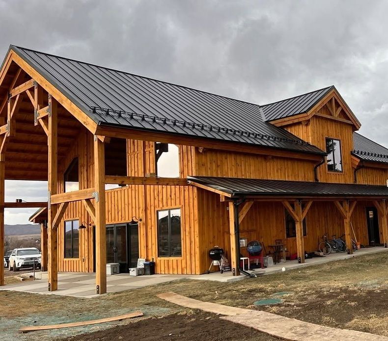 Wooden lodge-style building with a metal roof and covered porch under a cloudy sky