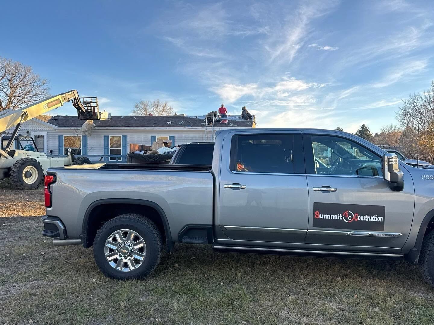 Gray pickup truck with roof-mounted equipment parked outdoors at a work site