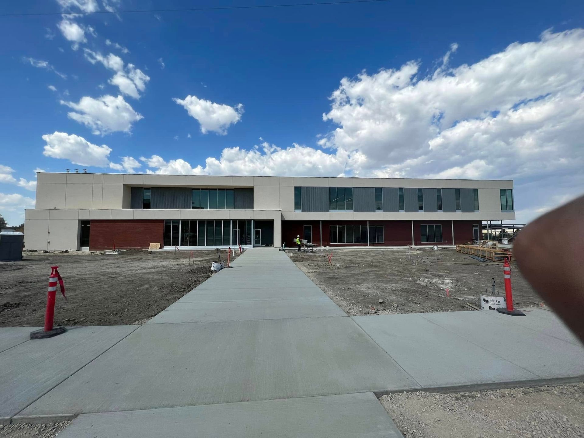 Modern two-story building with a central concrete walkway and red fire hydrants under a cloudy blue sky