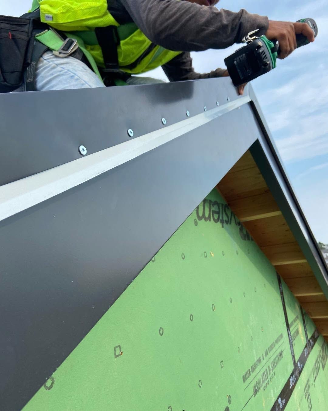 Worker installing metal roofing on a house under construction