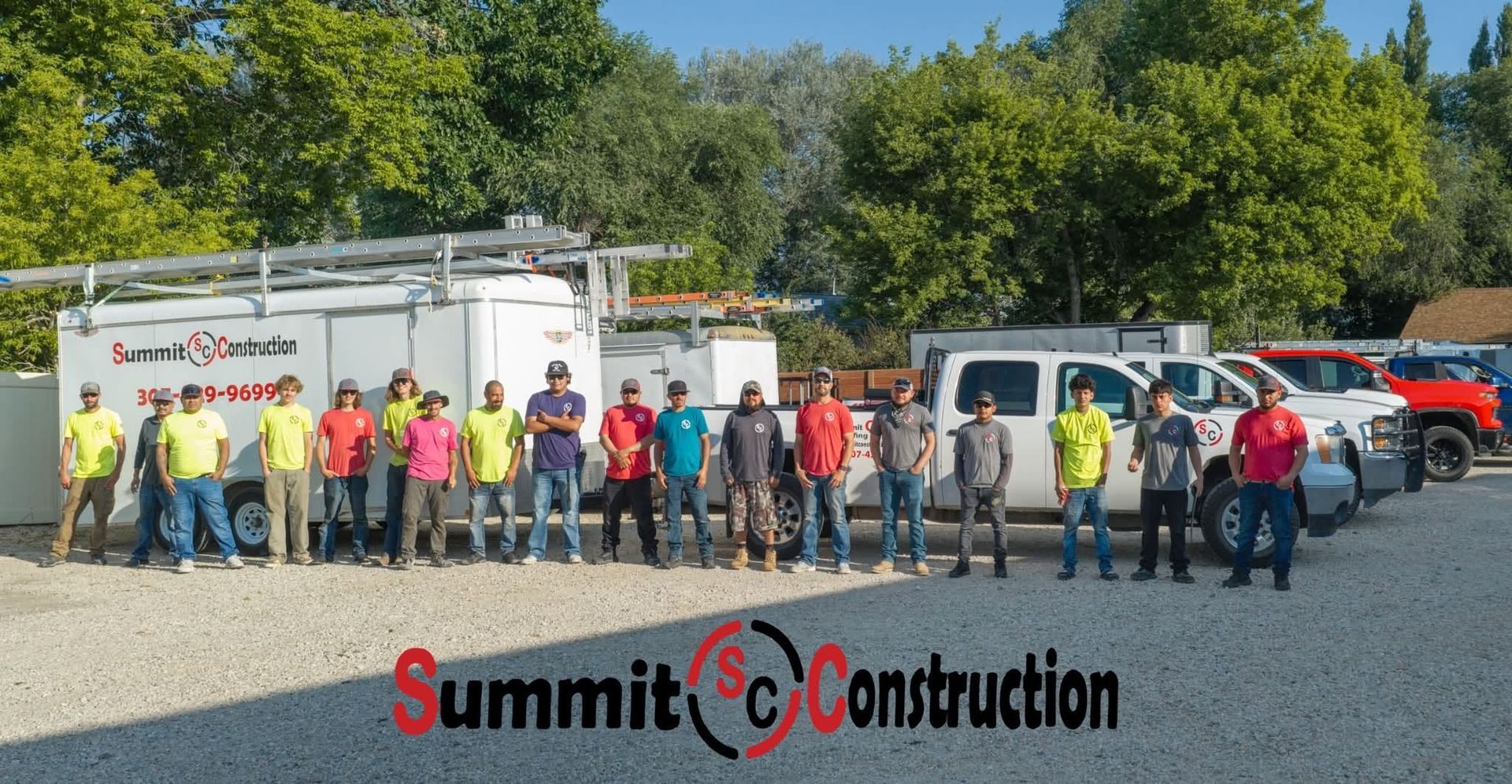 Construction crew lined up in front of trucks and a Summit Construction sign on a gravel lot