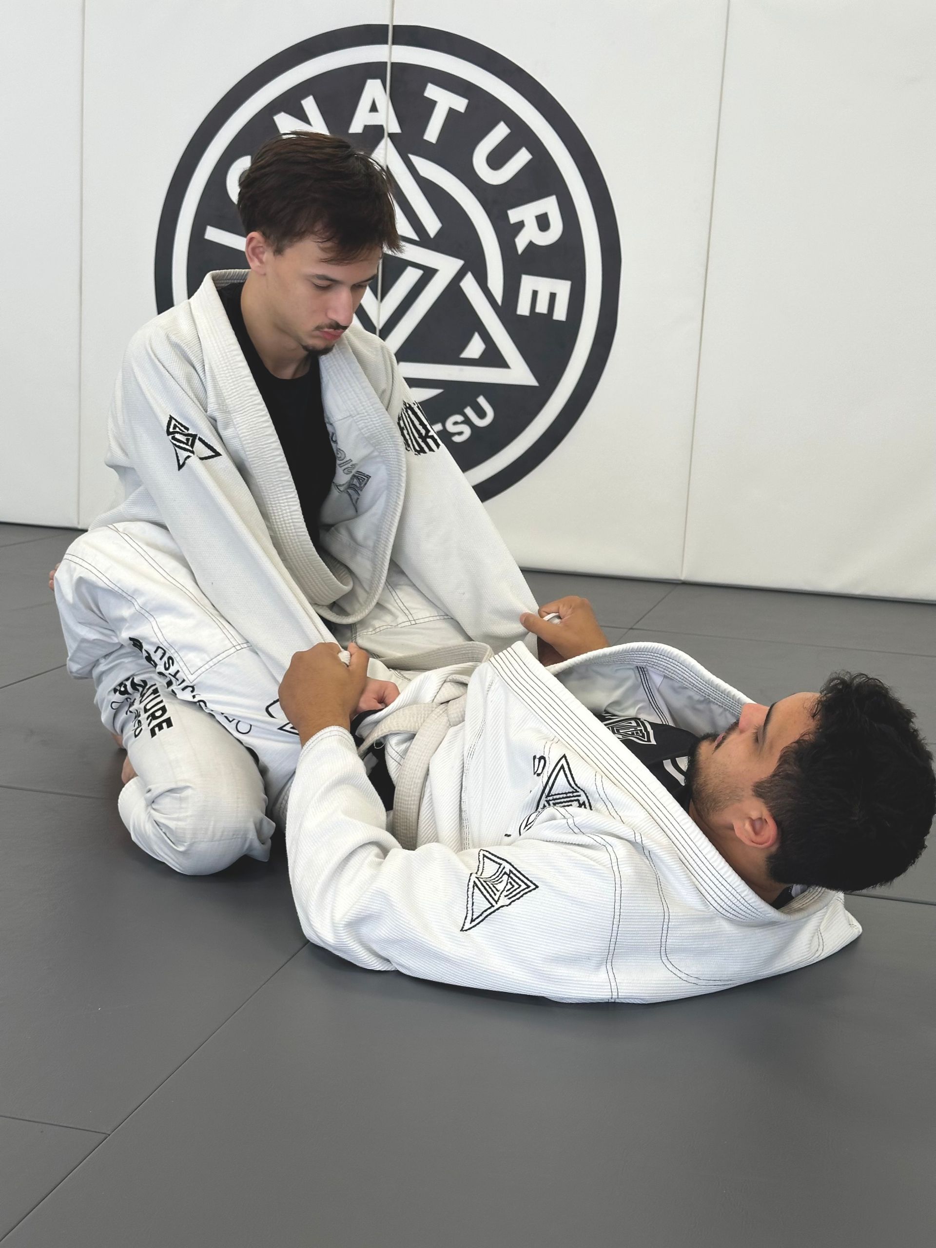 Adults drilling Brazilian Jiu-Jitsu techniques at Signature of Jiu-Jitsu in Belmont, CA to build strength and focus.