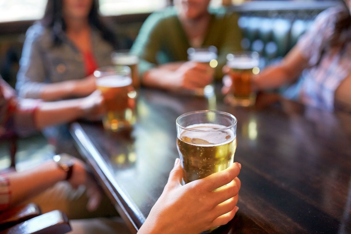 Group of people at a table, holding pints of beer in a bar — Maryborough Cricket Club In Maryborough, QLD