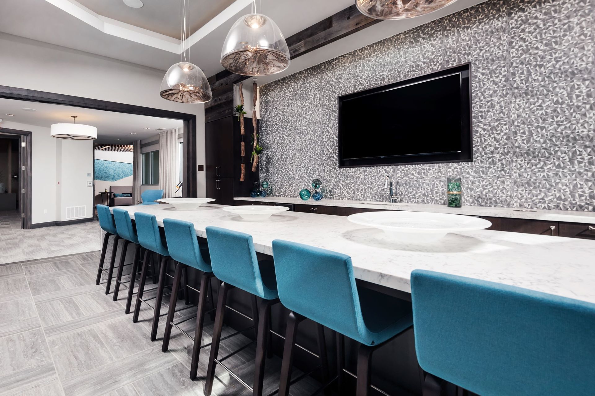 A long table with blue chairs and a flat screen tv on the wall.
