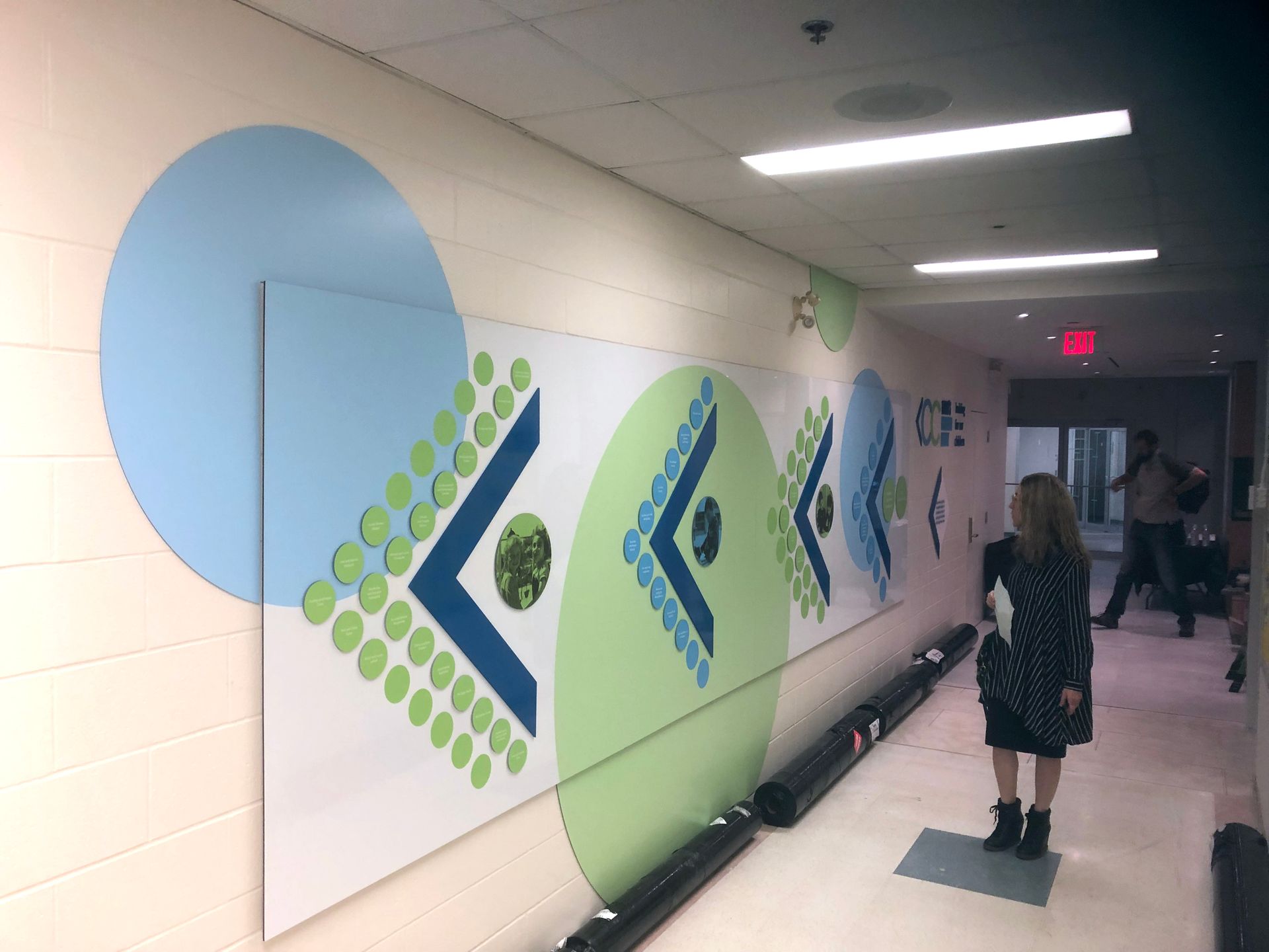 a woman is standing in a hallway with a large painting on the wall .